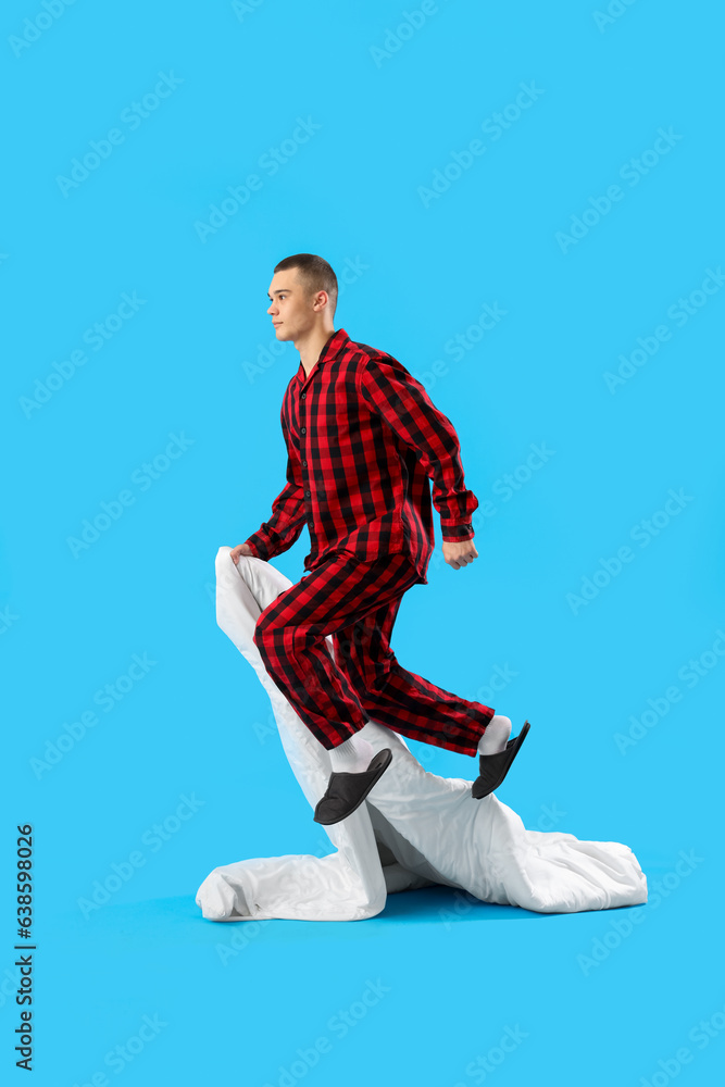 Jumping young man with blanket on blue background