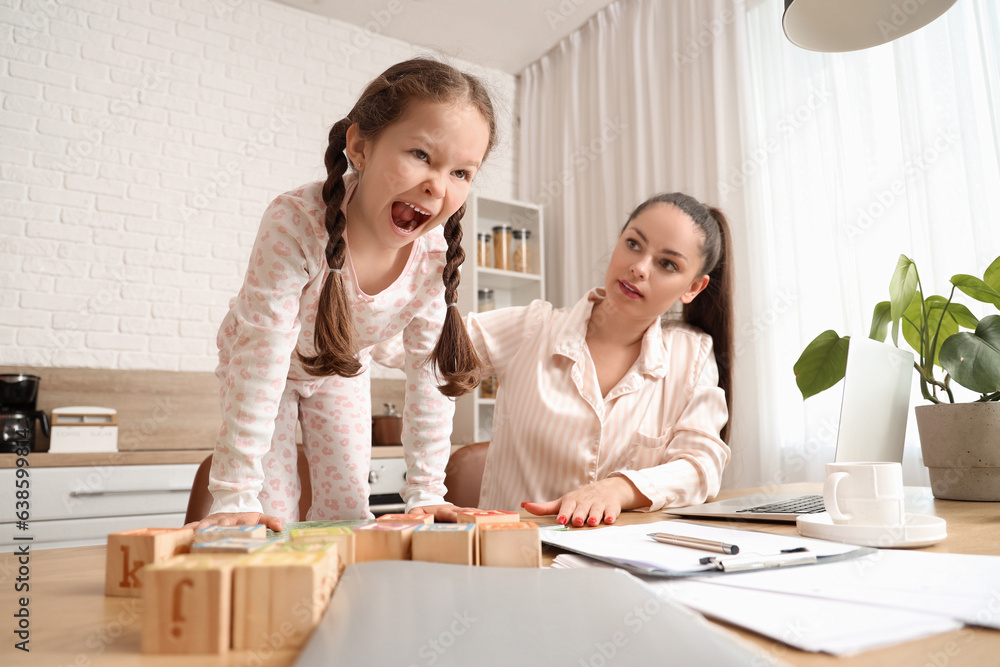 Working mother with her naughty little daughter in kitchen