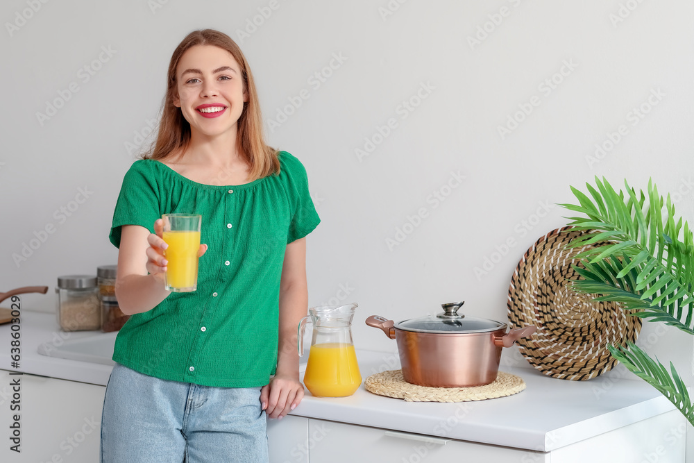 Young woman with glass of orange juice in kitchen