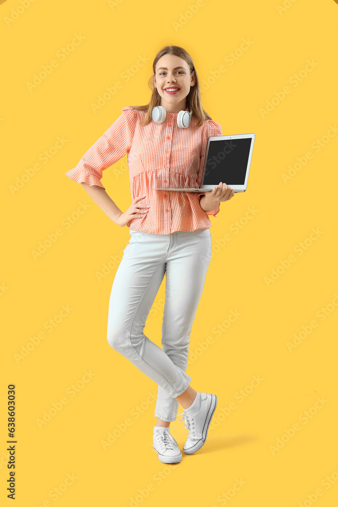 Female programmer with blank laptop on yellow background