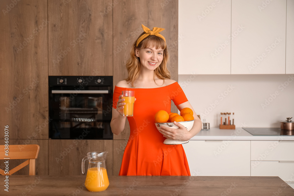 Young woman with glass of juice and oranges in kitchen