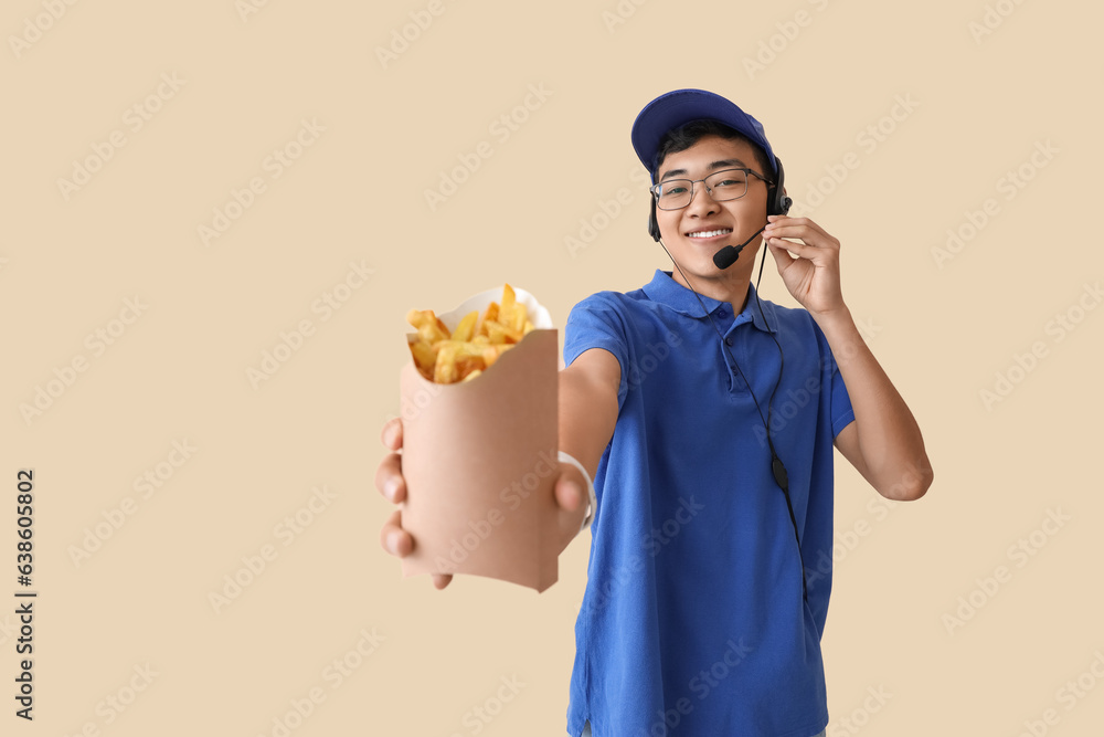 Young Asian worker with french fries on beige background