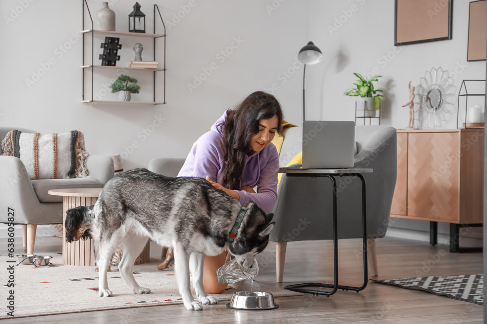 Young woman giving water to her dogs at home