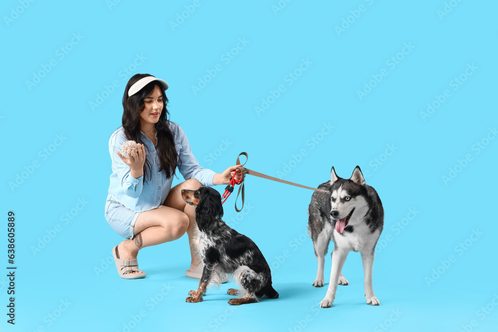 Young woman with coral and cute dogs on blue background