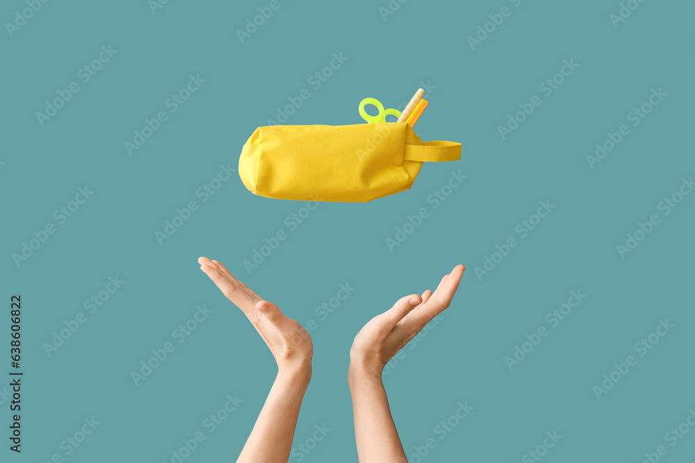 Female hands throwing pencil case with school supplies on blue background