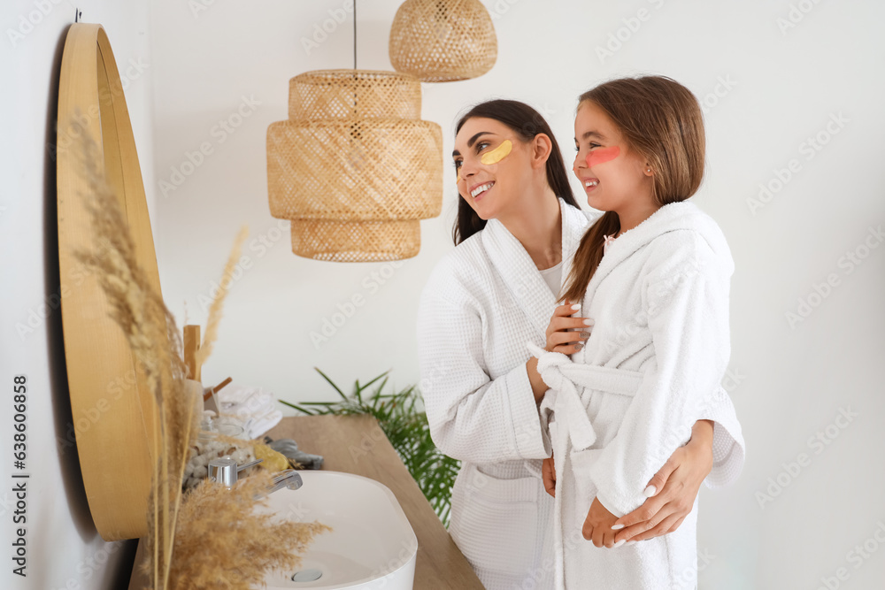 Happy mother and her little daughter with under-eye patches in bathroom