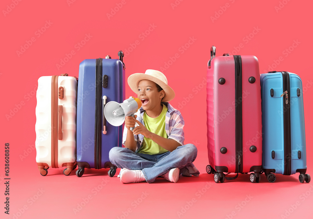 Little African-American boy with suitcases and megaphone on red background