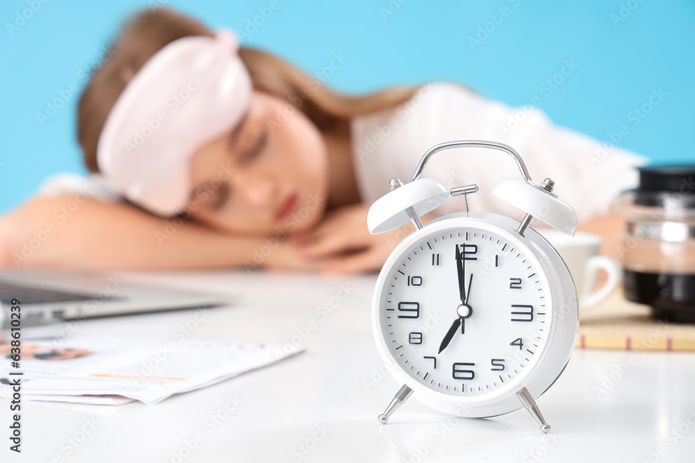 Alarm clock and sleeping woman on blue background