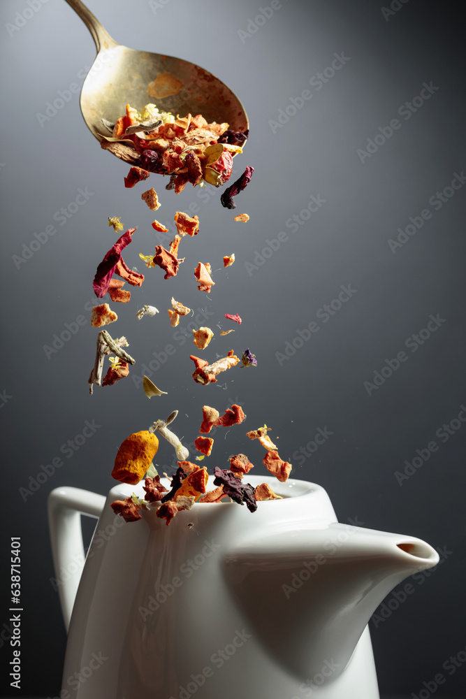 Dried herbs and flowers are poured into a teapot.