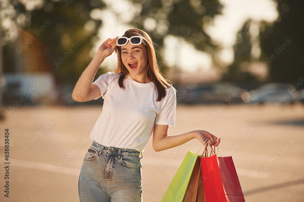 Excited for the sales. Beautiful woman in casual clothes is holding shopping bags, outdoors