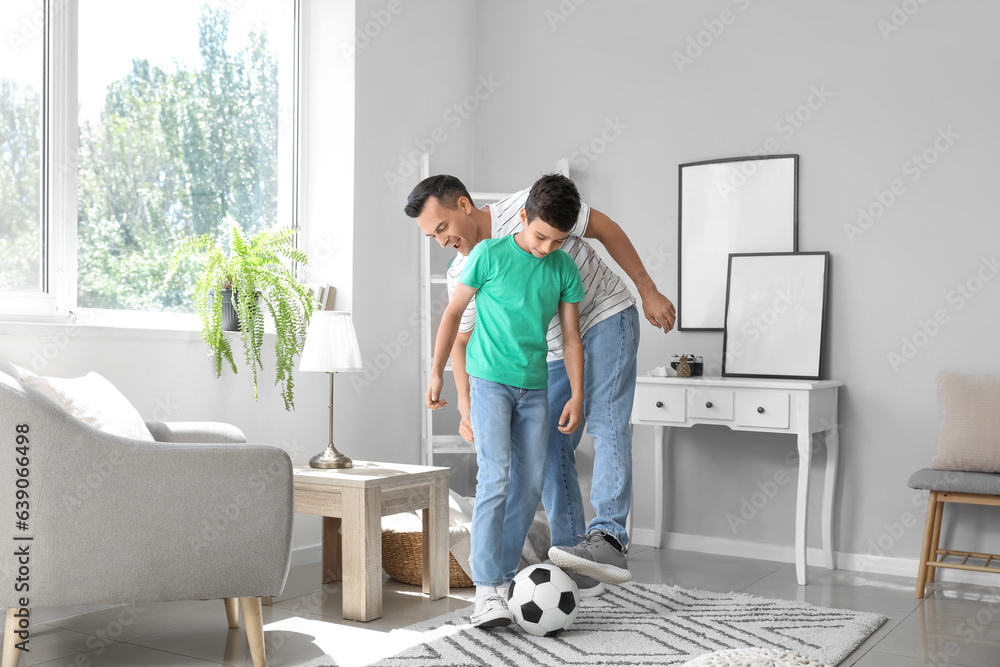 Little boy with his dad playing football at home