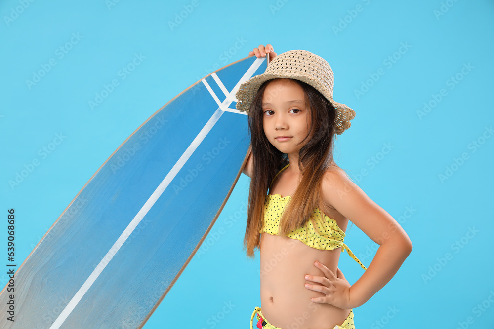 Little Asian girl with surfboard on blue background