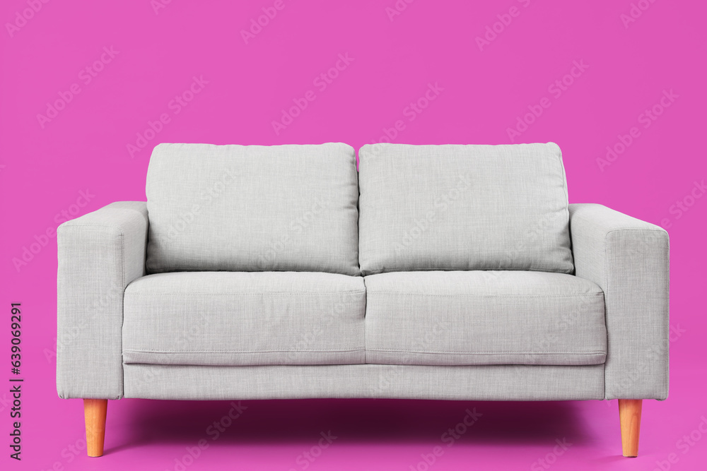 Cozy grey sofa on pink background