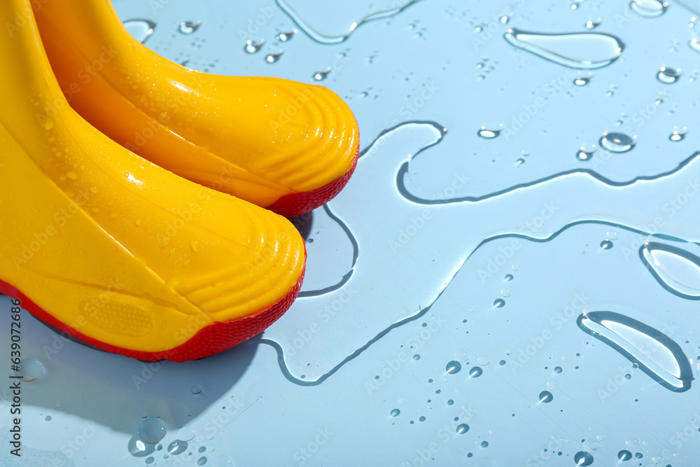 Yellow gumboots in water on blue background