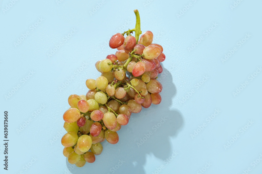 Tasty ripe grapes on blue background