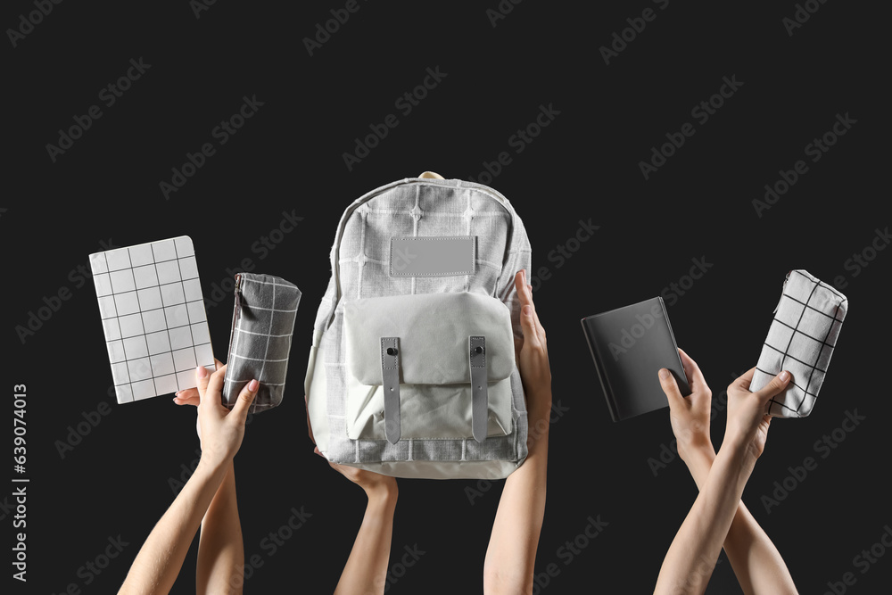 Many female hands with backpack and different stationery on black background