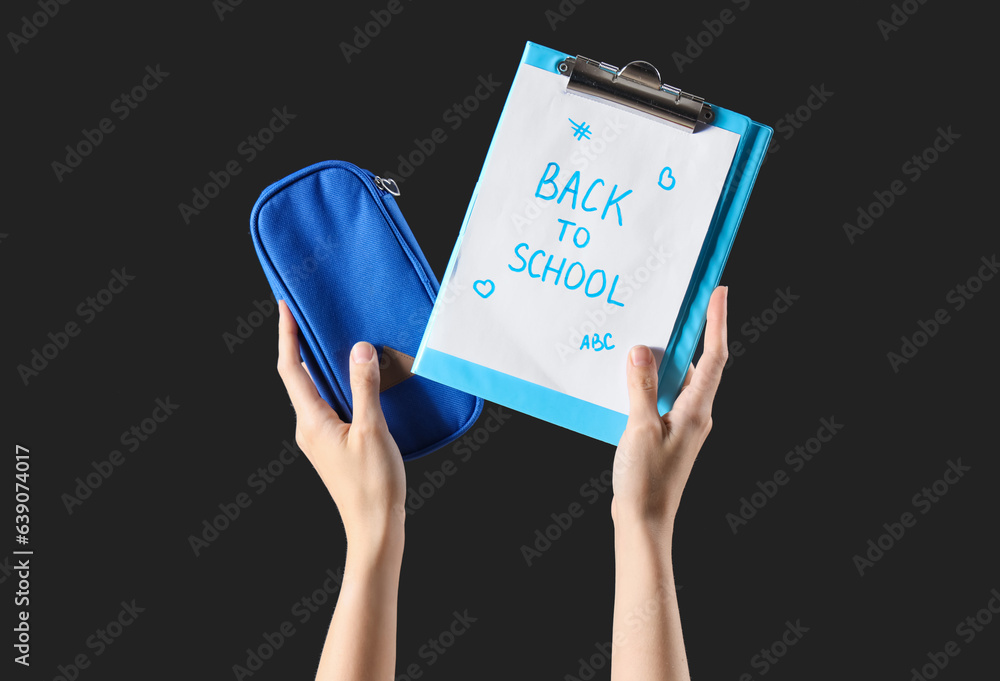 Female hands holding pencil case and notebook with text BACK TO SCHOOL on black background