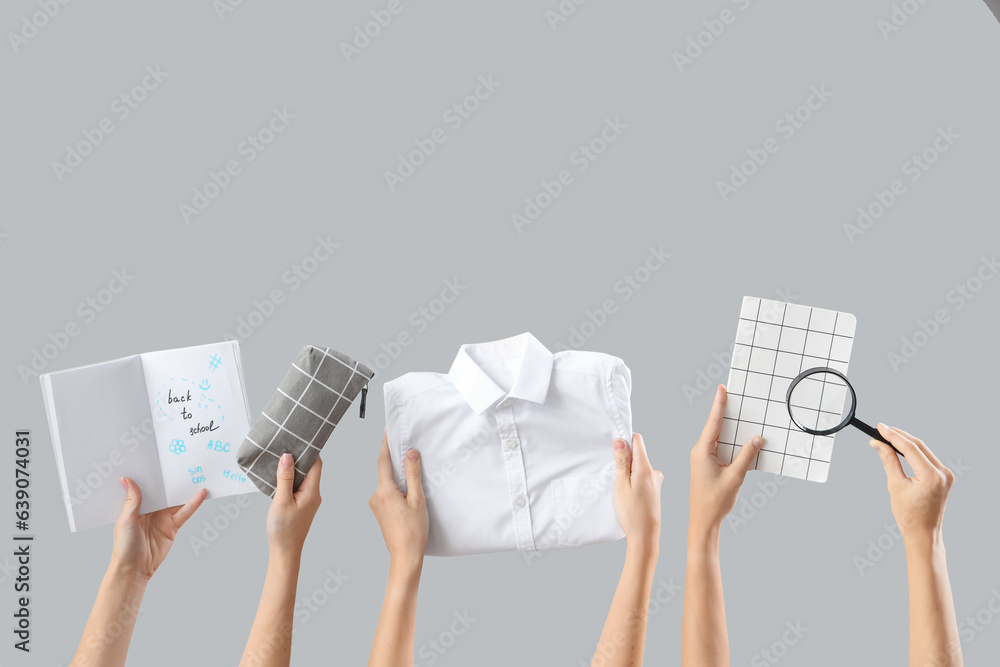 Female hands holding stationery, uniform and notebooks with text BACK TO SCHOOL on grey background