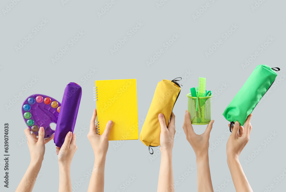 Many female hands with different stationery on grey background