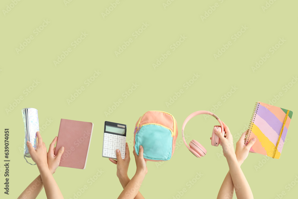 Female hands with backpack and different stationery on green background