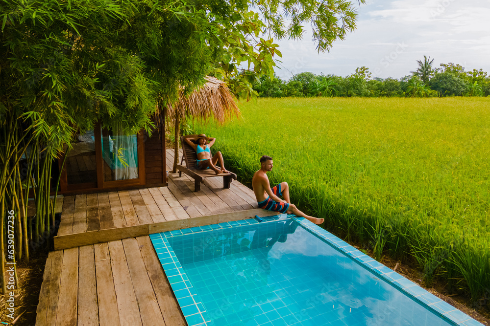 a couple of men and women in front of a Bamboo hut homestay farm, with Green rice paddy fields in Ce