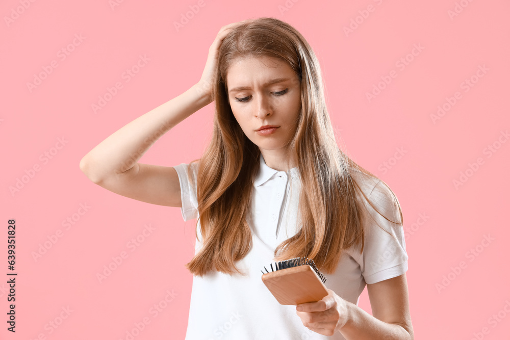 Worried young woman with hair loss problem and brush on pink background