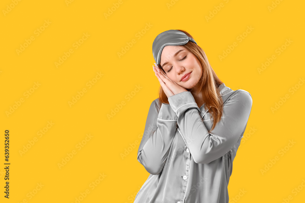 Young woman in pajamas on yellow background