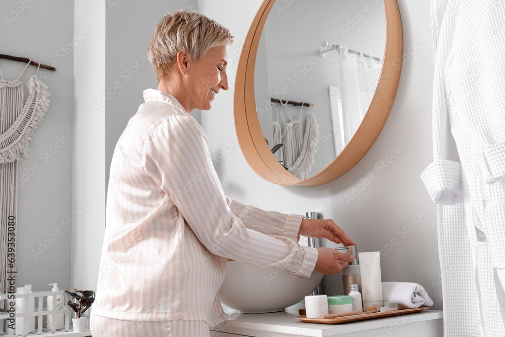 Mature woman with bottle of soap in bathroom