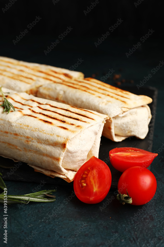 Board with tasty shawarma and tomatoes on dark background