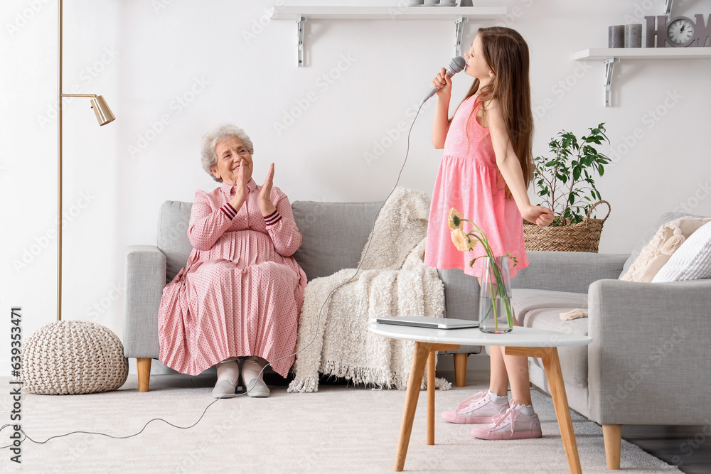 Senior woman and her little granddaughter singing at home