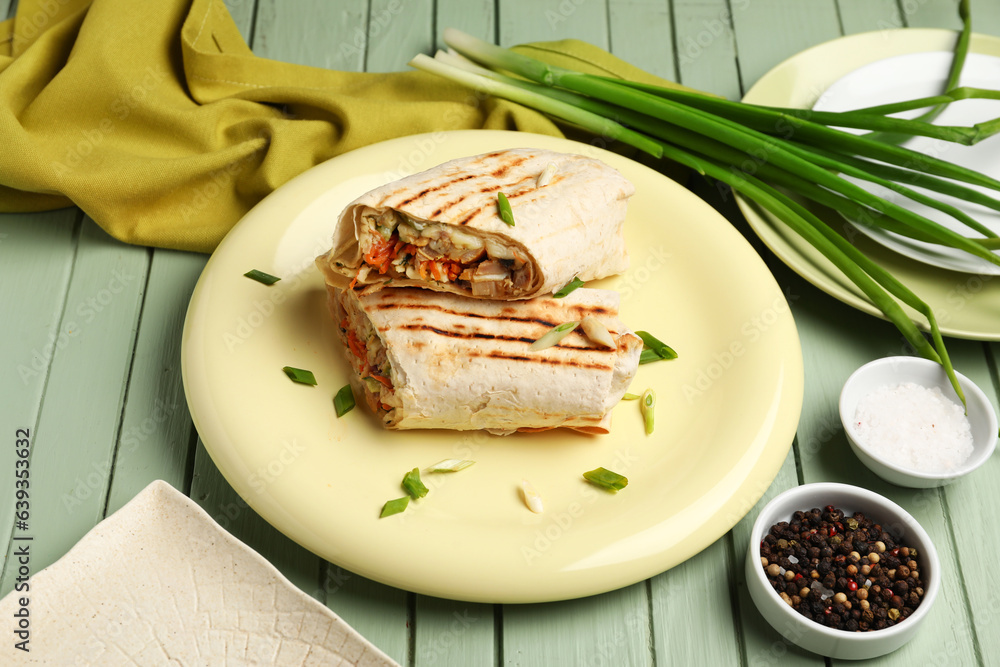 Plates of tasty shawarma with onion on green wooden background