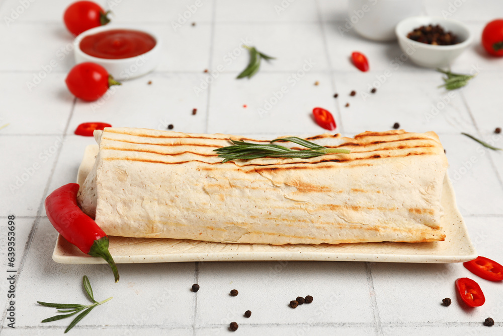 Plate of tasty shawarma with rosemary and chilli on white tile table