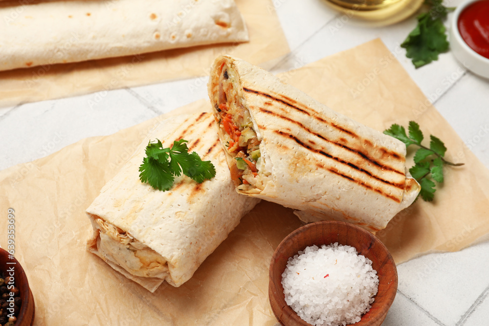 Baking paper with tasty shawarma with parsley on white tile table