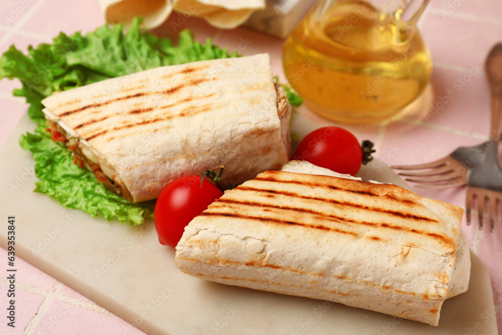 Board of tasty shawarma with lettuce and tomatoes on pink tile table