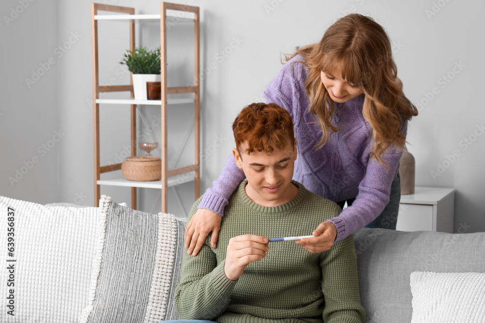 Young woman showing pregnancy test to her boyfriend at home