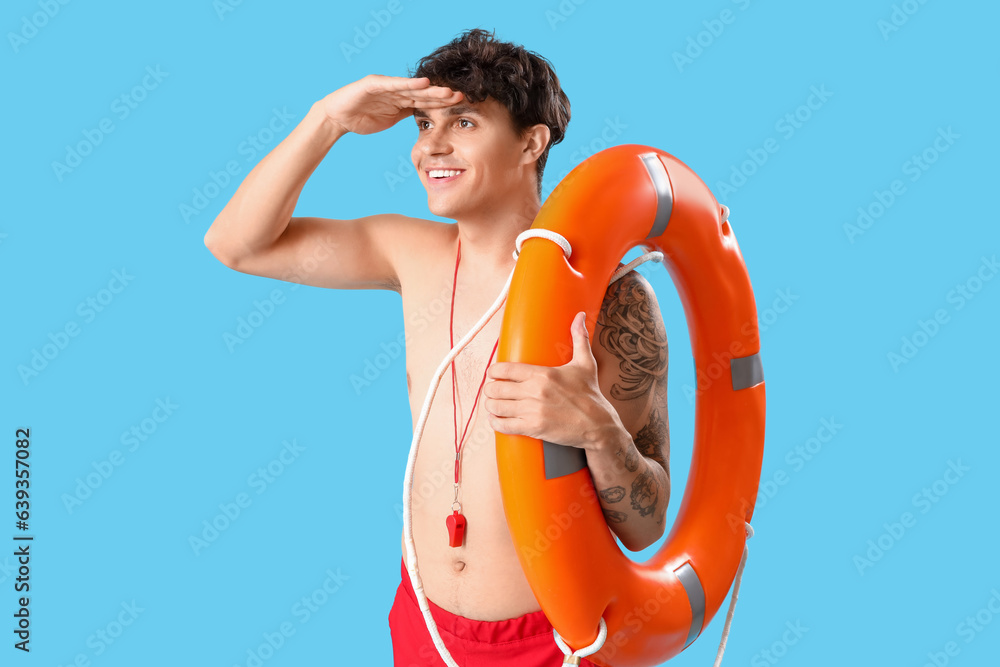 Male lifeguard with ring buoy on blue background