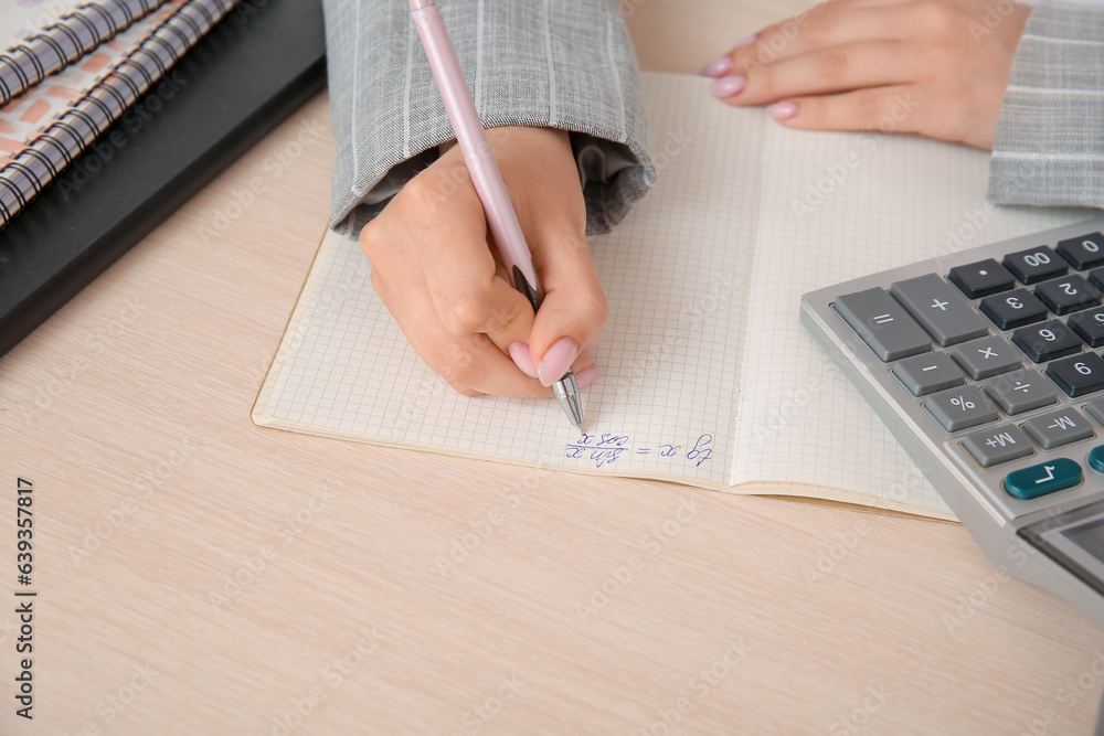 Female math teacher checking pupils homework at wooden table, closeup