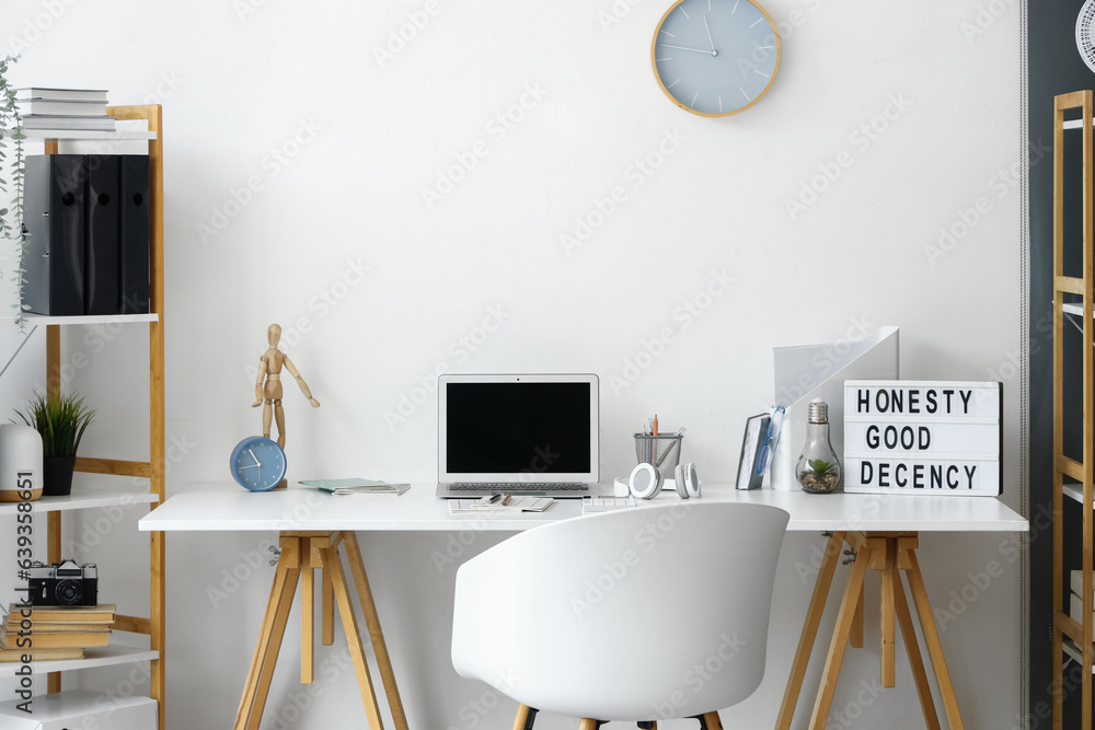 Modern workplace with laptop in interior of light office