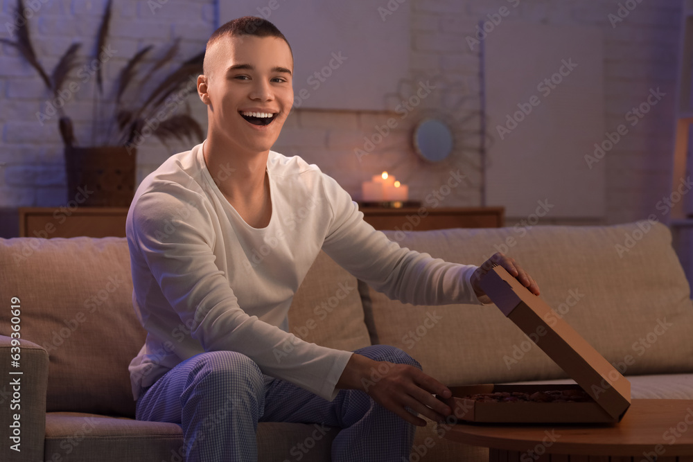 Hungry young man with tasty pizza at home late in evening