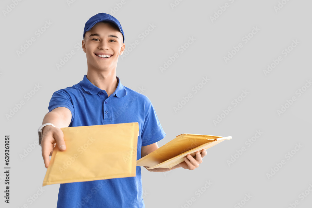 Young courier with envelopes on light background