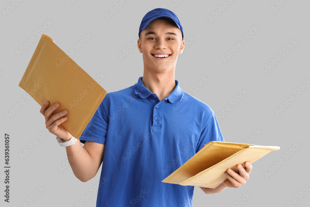 Young courier with envelopes on light background