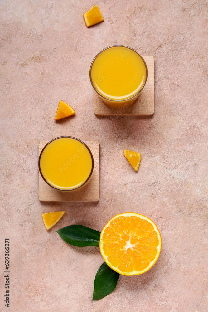 Glasses of fresh orange juice on beige background