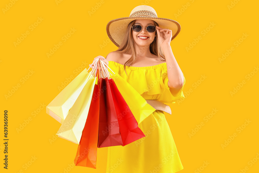 Pretty young woman with shopping bags on orange background