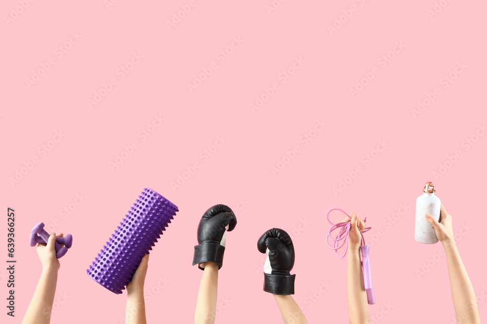 Female hands different sports equipment on pink background