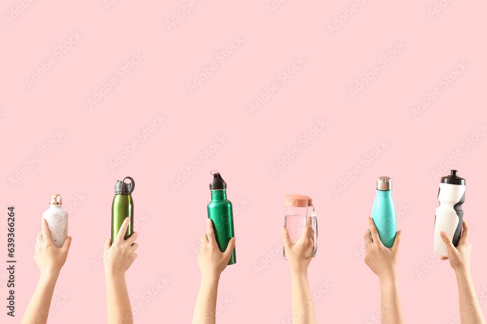 Female hands holding different bottles with sports drinks pink background