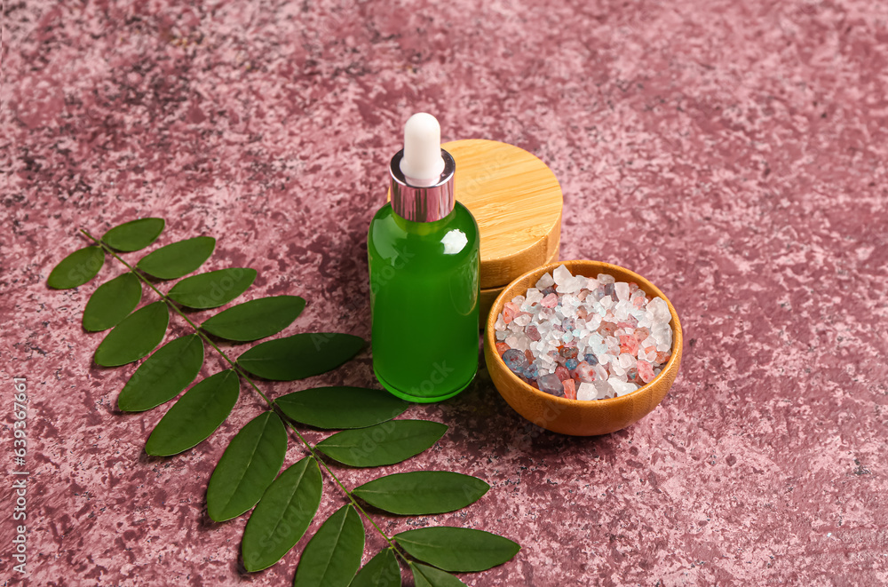 Bottle and jar of cosmetic products with sea salt on purple background