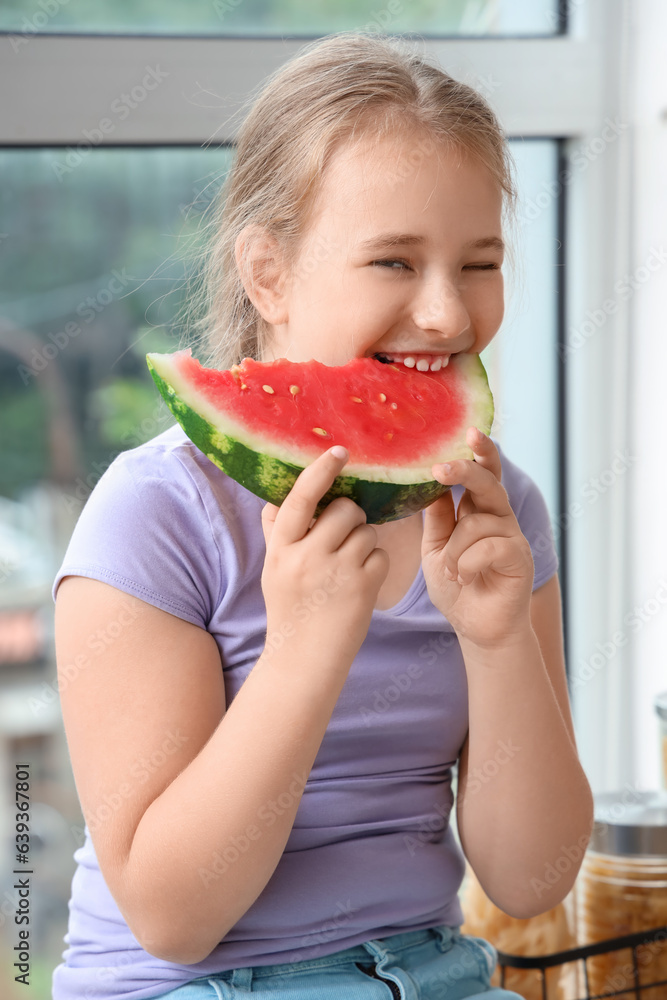 Little girl eating fresh watermelon in kitchen