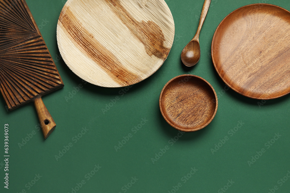 Different wooden tableware on green background