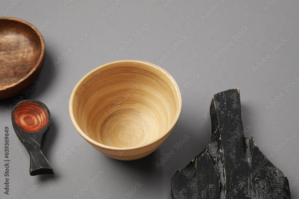 Different wooden tableware on grey background, closeup