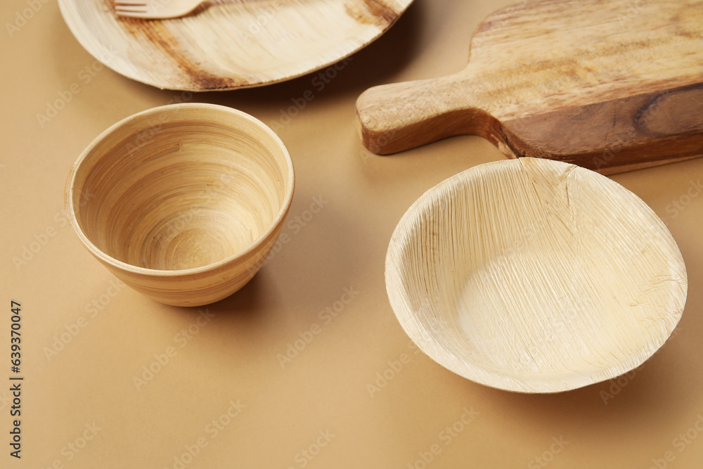 Different wooden tableware on beige background, closeup